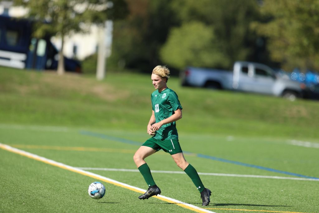 A player in green dribbles the ball upfield