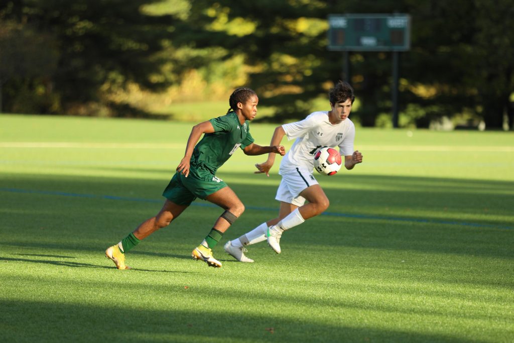 Two players chase the ball in a match