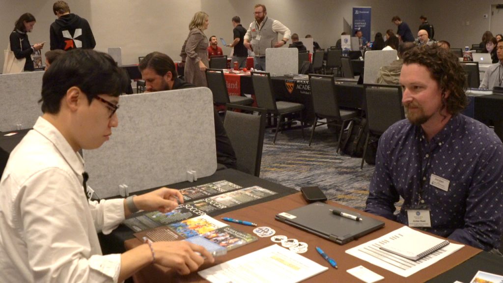 A boarding school admissions director in conversation across a table at the GESP conference, with other school tables behind